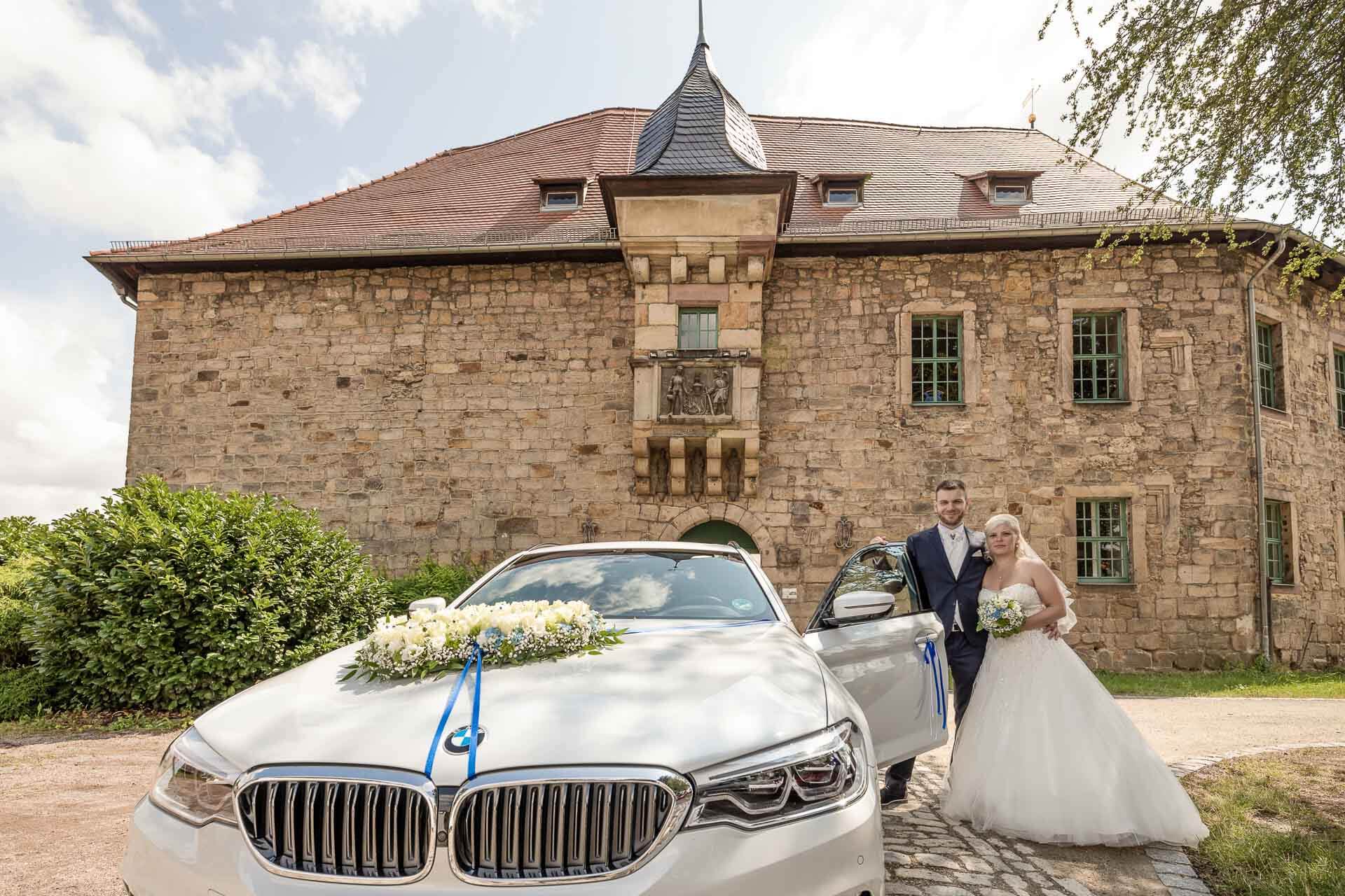 Frisch vermähltes Brautpaar vor dem Blankenhainer Schloss mit Brautauto
