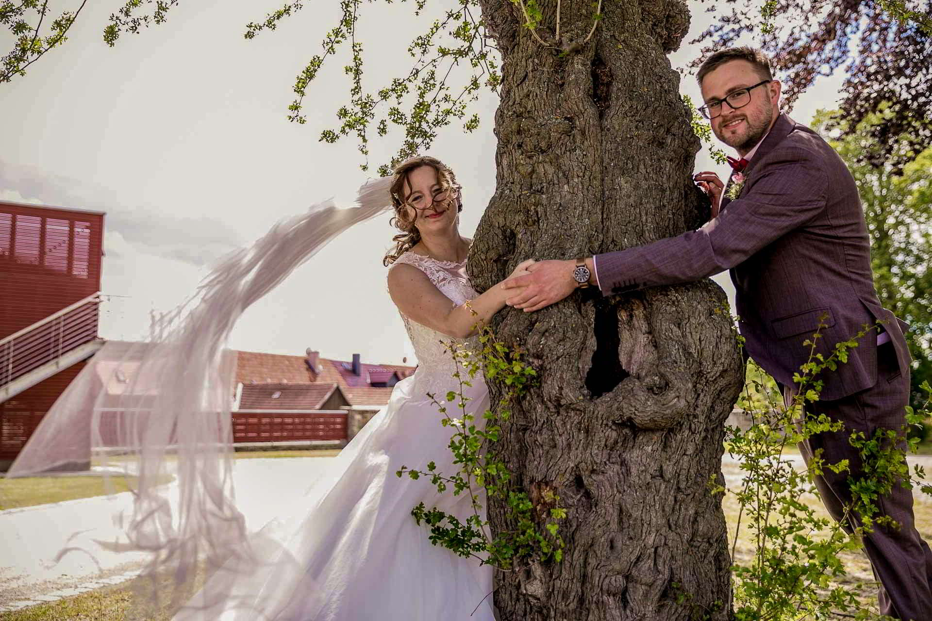 Brautpaar am Baum Brautpaar lacht an einem großen Baumstamm im Park